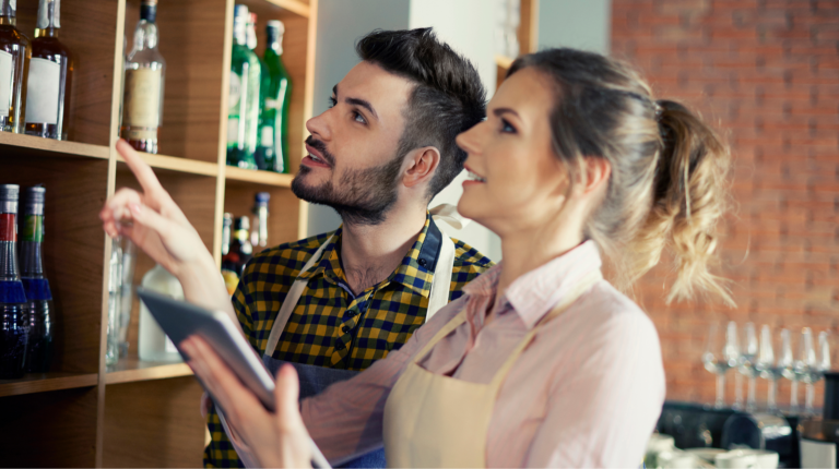 Bartenders reviewing liquor inventory and checking stock levels behind the bar