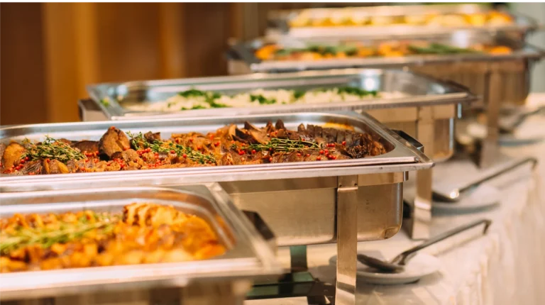 Buffet-style catering trays filled with hot food for a restaurant catering setup.